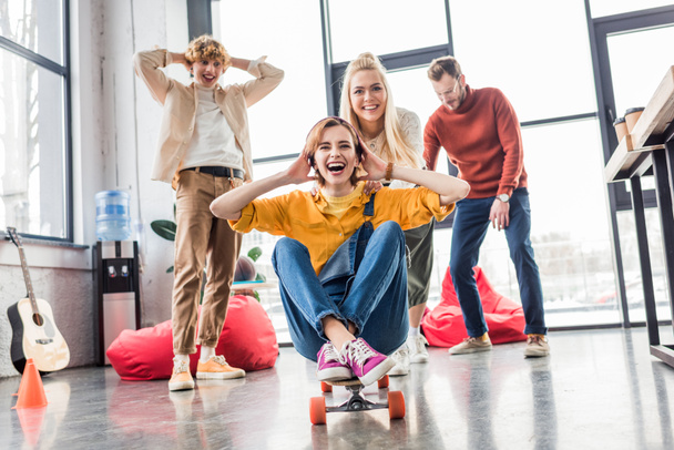 happy casual business colleagues having fun and riding skateboard in loft office - Zdjęcie, obraz