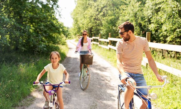 happy family with bicycles in summer park - Zdjęcie, obraz