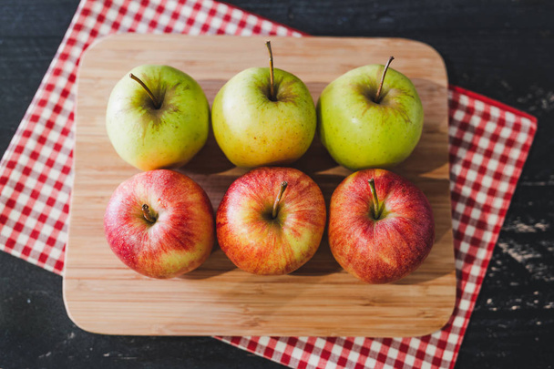 group of apples on wooden cutting board with napkin, close-up shot of organic products and healthy fruit - Photo, image