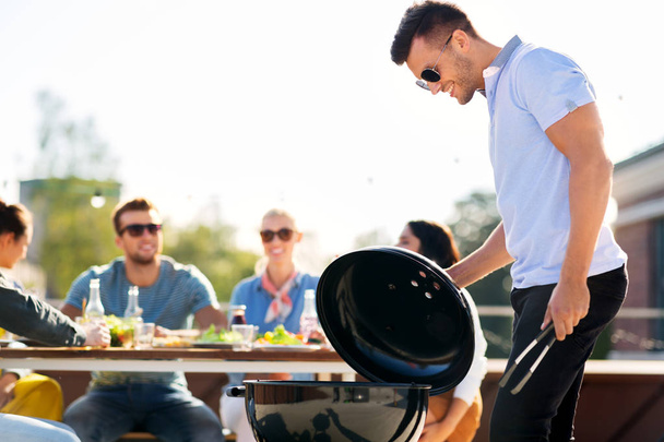 man grilling on bbq at rooftop party - 写真・画像