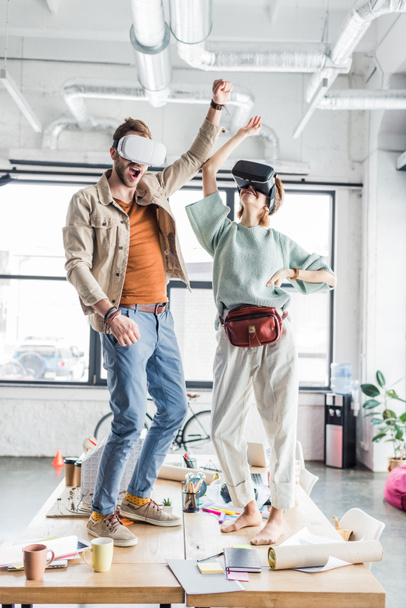female and male designers wearing vr headset, gesturing with hands and having virtual reality experience in loft office - Photo, Image