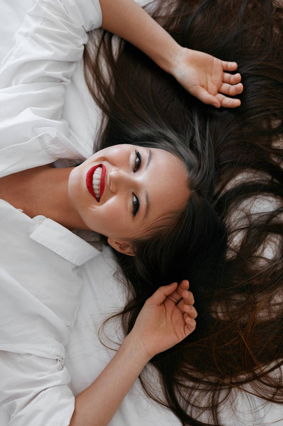 Beautiful woman with long hair, red lips makeup in white shirt - 写真・画像