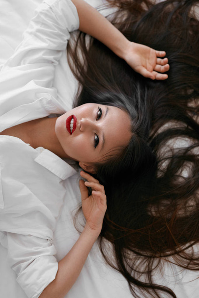Beautiful woman with long hair, red lips makeup in white shirt - Фото, изображение