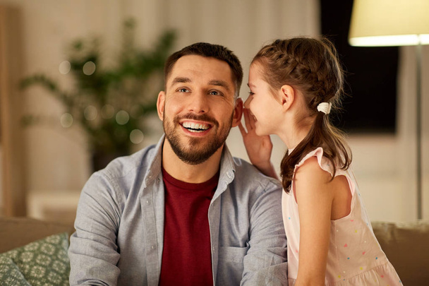 happy daughter whispering secret to father at home - Foto, Imagem
