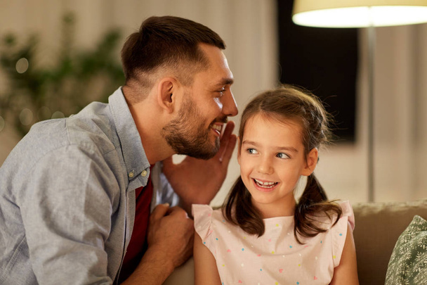 happy father whispering secret to daughter at home - Foto, Imagen