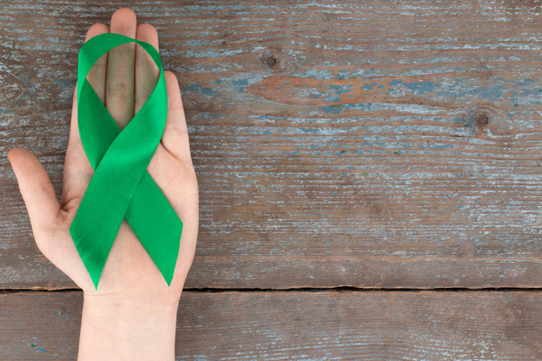 Green ribbon. Scoliosis, Mental health and other, awareness symbo on the wooden background with copy space. - Foto, afbeelding