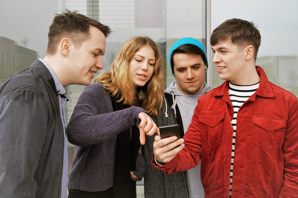 εφηβική παρέα, έχοντας μια συζήτηση πάνω από κάποιο περιεχόμενο κινητό τηλέφωνο - Φωτογραφία, εικόνα