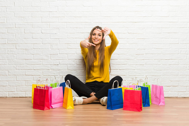 Young girl with lot of shopping bags focusing face. Framing symbol - Photo, Image