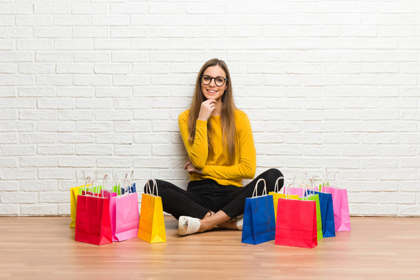 Jong meisje met veel winkelen zakken met glazen en glimlachen - Foto, afbeelding