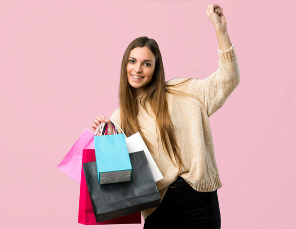 Девушка с пакетами для покупок празднует победу на изолированном розовом фоне
 - Фото, изображение