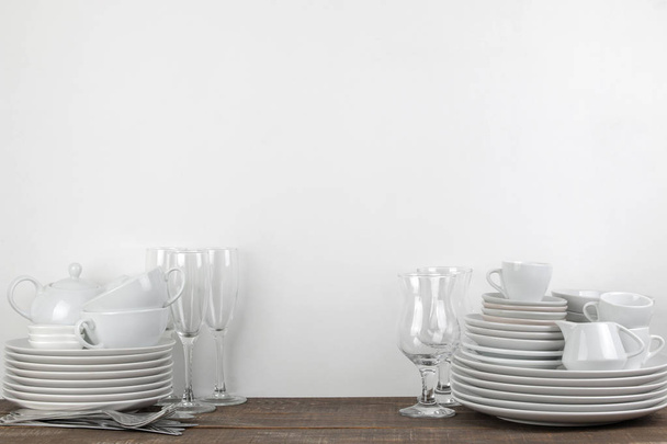 Una pila di piatti. stoviglie su un tavolo di legno marrone. piatti per servire la tavola. piatti e posate, tazze e teiera, bicchieri. con spazio per testo
 - Foto, immagini