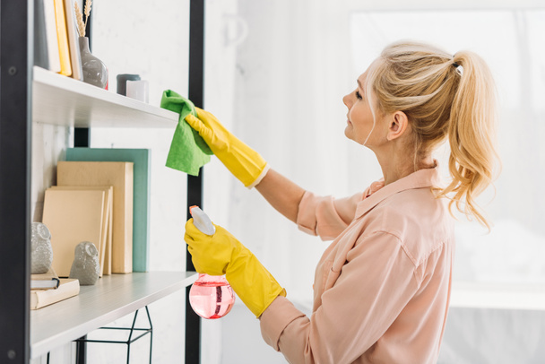 Senior woman with pony tail cleaning shelves with rag - Photo, Image