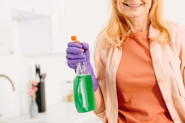 Cropped view of smiling senior woman in rubber glove holding spray - Фото, зображення