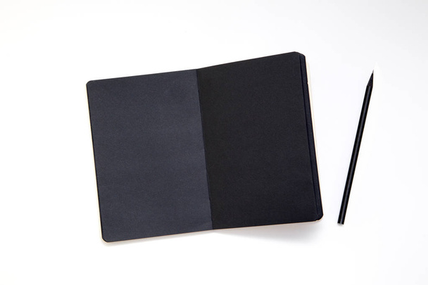 Notebook with black paper and pencil on white background. Workplace of the artist or writer. top view. close-up, mockup. - Fotografie, Obrázek