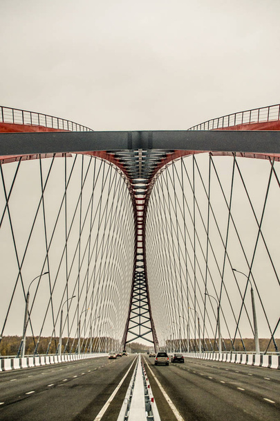 Beautiful background and view, landscape and panorama of a modern cable-stayed arched type of red bridge against the sky. - Фото, зображення