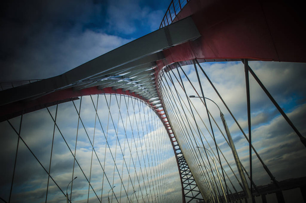 Beautiful background and view, landscape and panorama of a modern cable-stayed arched type, red bridge against the blue sky with clouds. - Zdjęcie, obraz