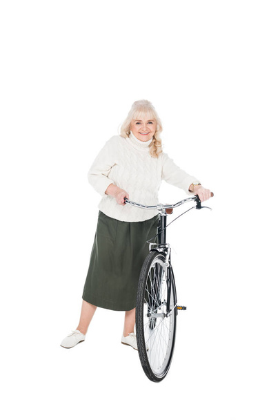 smiling senior woman standing with bicycle isolated on white - Photo, Image