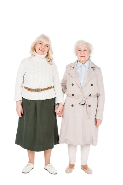 cheerful retired women holding hands isolated on white - 写真・画像