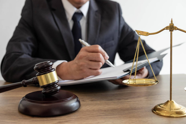Legal law, advice and justice concept, counselor lawyer or notary working on a documents and report of the important case and wooden gavel, brass scale on table in courtroom. - Photo, Image