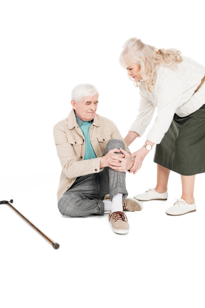 hombre mayor sosteniendo la rodilla mientras tiene dolor artritis cerca de esposa cariñosa aislado en blanco
 - Foto, imagen