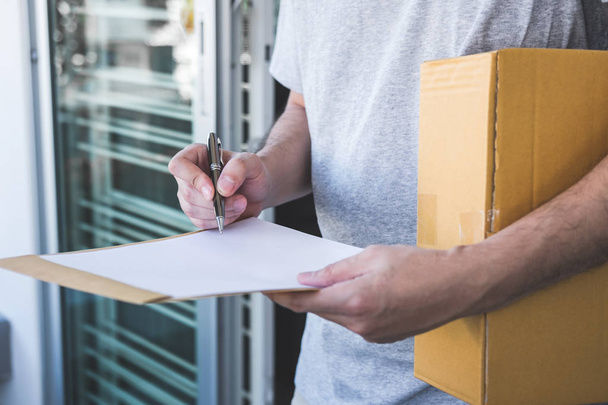 Delivery mail man giving parcel box to recipient and signature form, Young owner signing receipt of delivery package from post shipment courier, Home delivery service and working with service mind. - Φωτογραφία, εικόνα