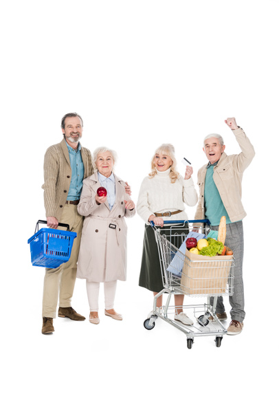 personas mayores felices de pie cerca de la mujer jubilada con tarjeta de crédito aislada en blanco
 - Foto, Imagen