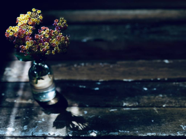 美しい花というランタナ カマラや素朴な木製のテーブル背景にガラス瓶の金の布   - 写真・画像