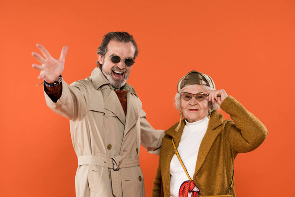 élégant couple retraité debout et souriant sur fond orange
 - Photo, image