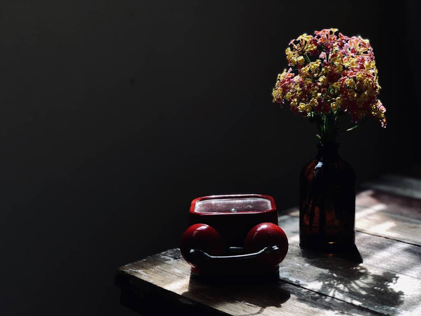 素朴な木製のテーブルに暗いガラス瓶と赤のビンテージ目覚まし時計の美しいランタナ カマラの花のクローズ アップ ビュー - 写真・画像