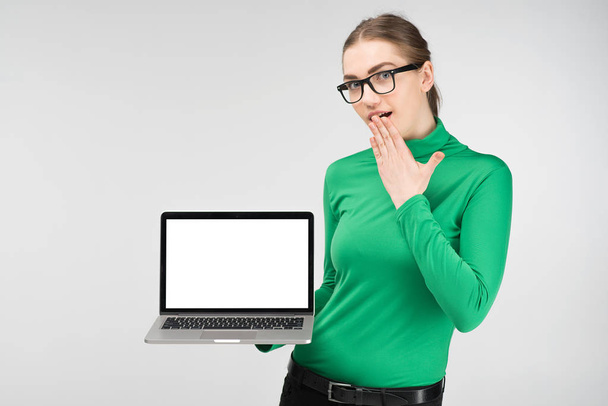 Estudiante chica sostiene un ordenador portátil en sus manos y sorprendido. - Imagen
 - Foto, imagen