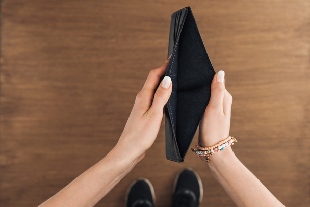 top view of woman holding empty wallet on wooden background - Photo, Image