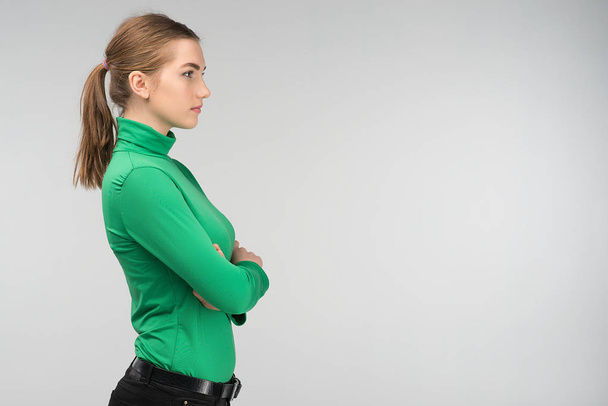 Primo piano vista laterale di una giovane donna triste in piedi con le braccia incrociate isolate sullo sfondo. - Immagine
 - Foto, immagini