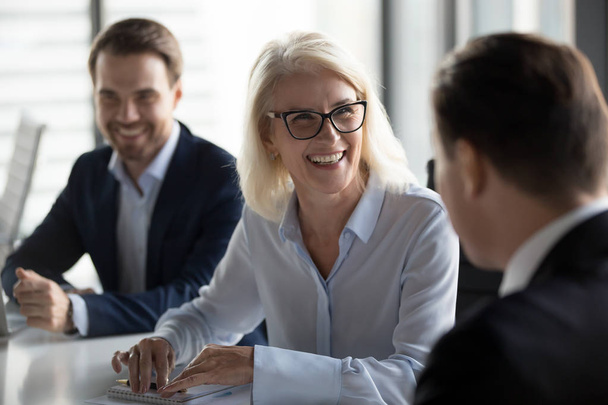 Friendly middle aged female leader laughing at group business meeting - Photo, Image