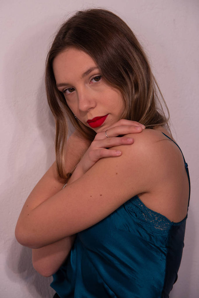 Portret van de halve lengte van blond meisje in blauw satijn tank top met kant. Concept van knuffelen. Perfecte make-up met rode lippen. Witte achtergrond. - Foto, afbeelding