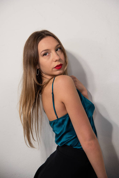 Half-length portrait of blonde girl in blue satin tank top with lace. Perfect makeup with red lips. White background. Copy space. - Photo, Image