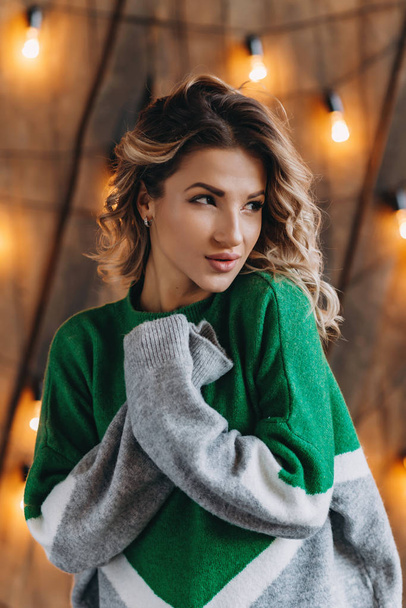Nahaufnahme Porträt einer Frau im grünen Pullover vor einer Lichtwand - Foto, Bild