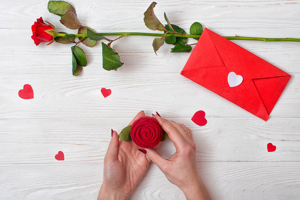 A woman holds a box with a ring a gift from a loved one.Valentines Day background with a red rose, a gift and an envelope with a valentine card. - Zdjęcie, obraz
