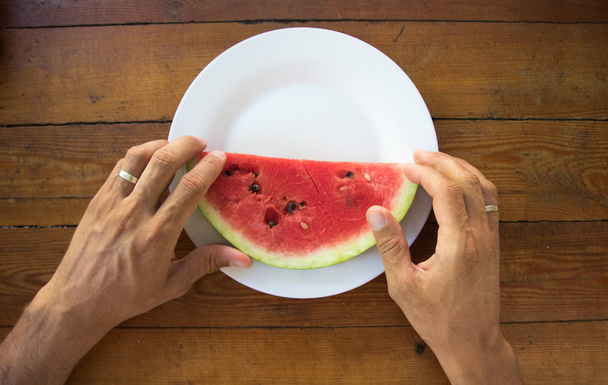 a slice of ripe watermelon in a mans hand, close up - Foto, Imagem