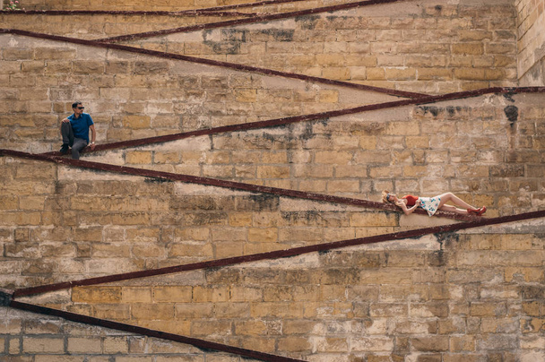 Мужчина и женщина лежат на городских стенах, в старом городе Трех Городов, Мальта
 - Фото, изображение