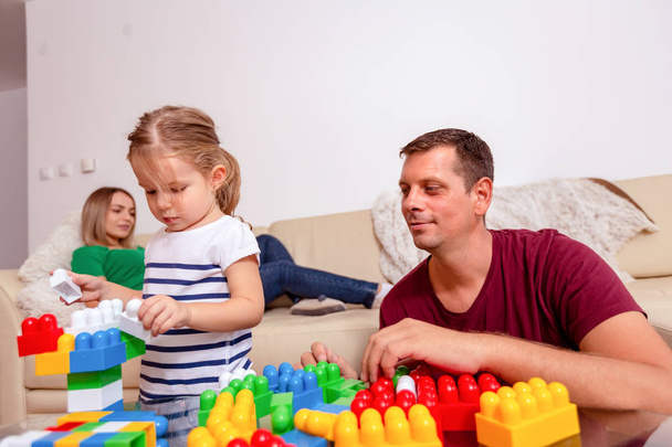 Усміхнений батько і мила дочка грає з кубиками вдома
 - Фото, зображення