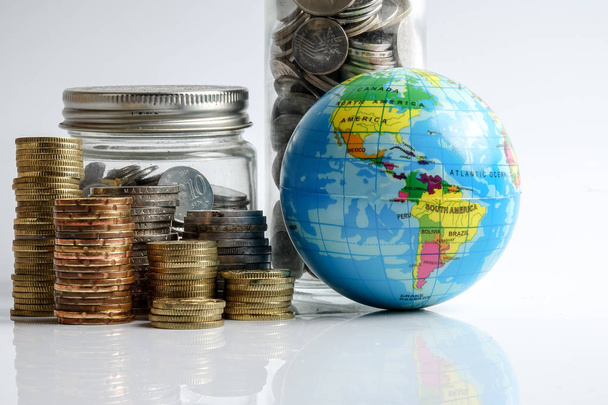 Wereldeconomie concept met bol globe en gestapeld van munten over Wit. - Foto, afbeelding