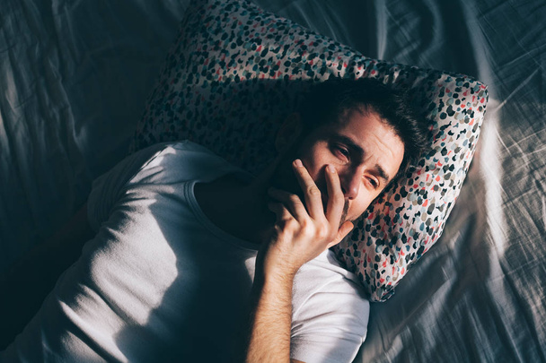 Młody człowiek przygnębiony płacz w łóżku - Zdjęcie, obraz