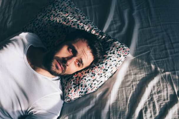 Young depressed man crying in bed - Φωτογραφία, εικόνα