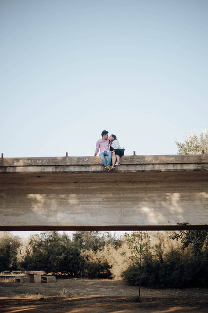 young couple in love kissing on an old bridge at sunset - Фото, изображение