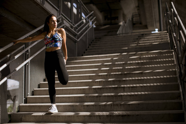 Joven mujer fitness haciendo ejercicios al aire libre en el medio ambiente urbano
 - Foto, Imagen
