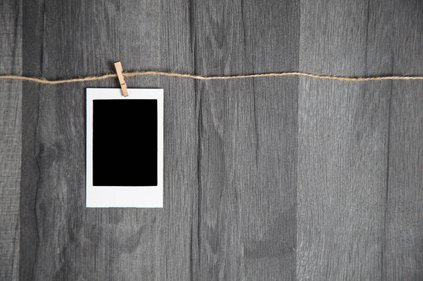 Blank vintage instant photo with empty space hanging on rope on wooden background - Φωτογραφία, εικόνα