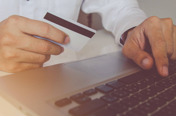 Человек держит кредитную карту и с помощью ноутбука делает онлайн оплату, онлайн покупки
 - Фото, изображение