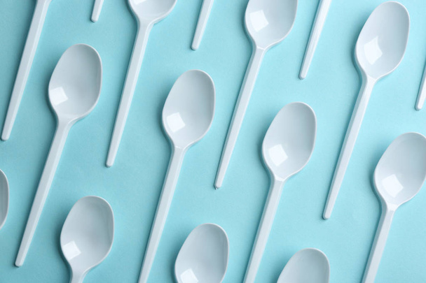 Flat lay composition with plastic spoons on color background. Table setting - Foto, imagen