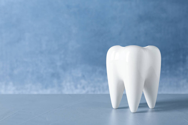 Ceramic model of tooth on table against color background. Space for text - Zdjęcie, obraz