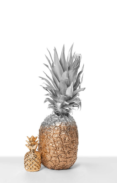 Silber und Gold bemalte Ananas mit niedlichem Dekor auf weißem Hintergrund - Foto, Bild